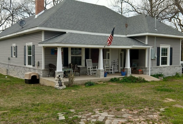 rear view of property featuring a yard, a chimney, and a shingled roof