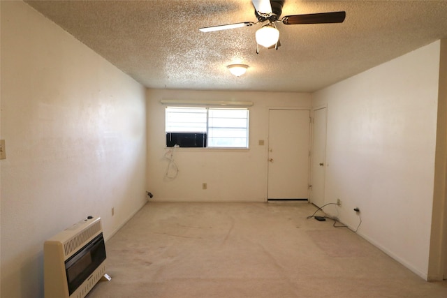 empty room with heating unit, ceiling fan, a textured ceiling, and light colored carpet