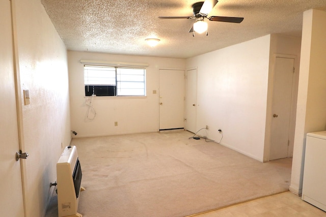 empty room with a textured ceiling, heating unit, a ceiling fan, and light carpet