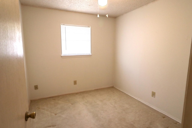 spare room with baseboards, light carpet, and a textured ceiling
