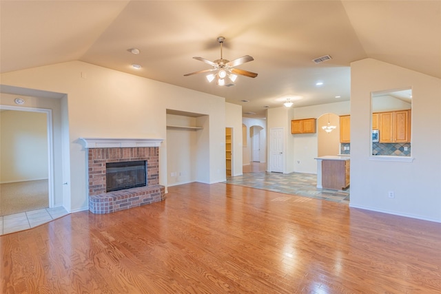 1032 Bending Oak Dr, Cedar Hill, TX 75104 - unfurnished living room featuring lofted ceiling, ceiling fan, arched walkways, light wood-style flooring, and a brick fireplace