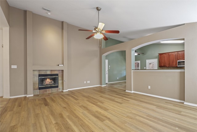 11279 Snyder Dr, Frisco, TX 75035 - unfurnished living room with ceiling fan, arched walkways, a tile fireplace, light wood finished floors, and baseboards