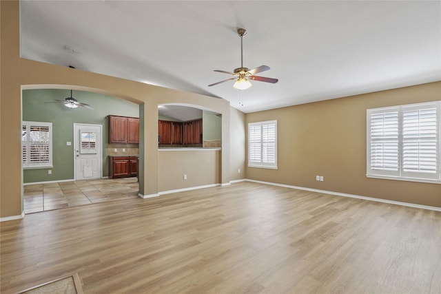 11279 Snyder Dr, Frisco, TX 75035 - unfurnished living room featuring ceiling fan, light wood-type flooring, lofted ceiling, baseboards, and arched walkways