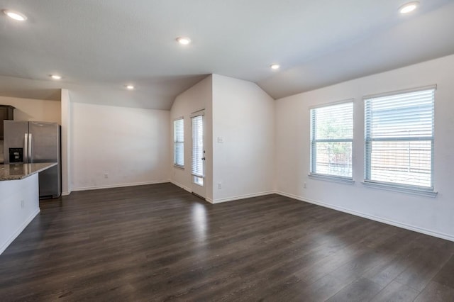 unfurnished living room featuring a wealth of natural light, dark wood-type flooring, and vaulted ceiling