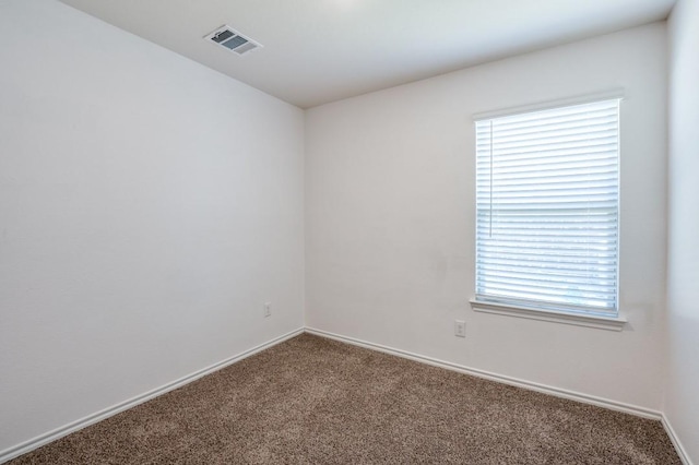 spare room with carpet flooring, baseboards, and visible vents