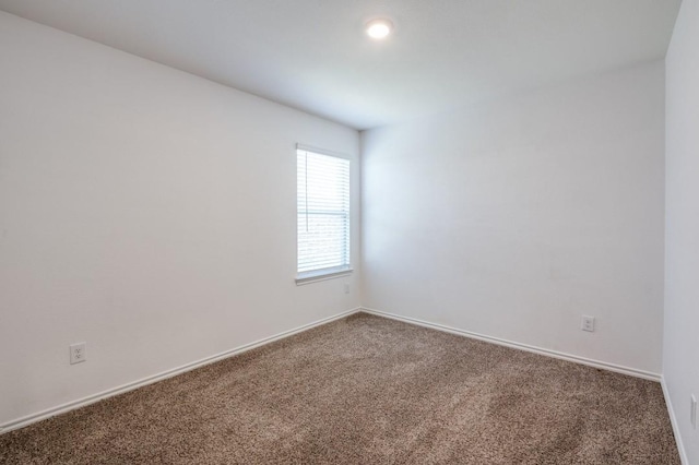 carpeted empty room featuring baseboards