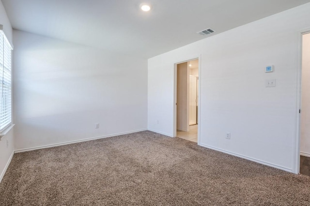 empty room featuring light carpet, visible vents, and baseboards