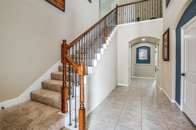 9848 Robinwoods Dr, Frisco, TX 75035 - stairway featuring arched walkways, tile patterned floors, a towering ceiling, and baseboards