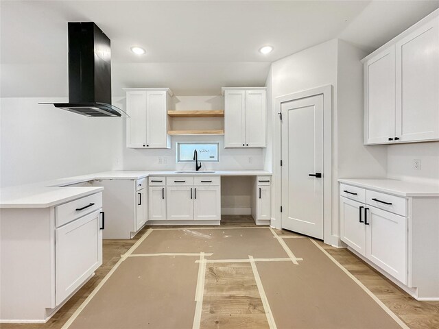 kitchen with a sink, light wood-type flooring, open shelves, and range hood