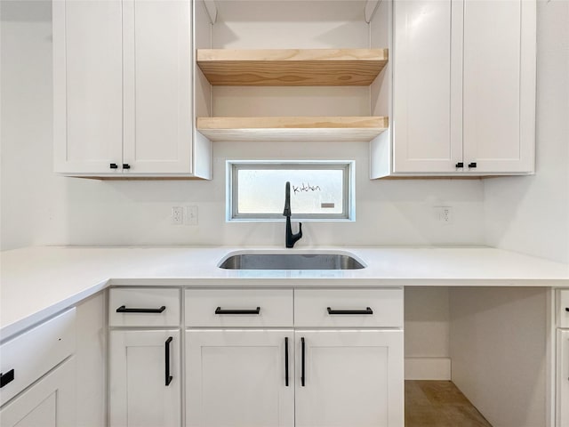 kitchen with a sink, white cabinets, and light countertops