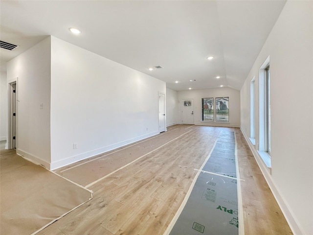 unfurnished living room featuring visible vents, baseboards, light wood-type flooring, vaulted ceiling, and recessed lighting