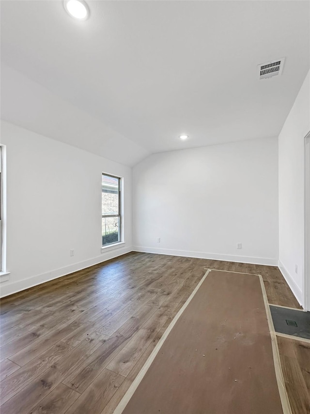spare room featuring visible vents, wood finished floors, recessed lighting, baseboards, and lofted ceiling