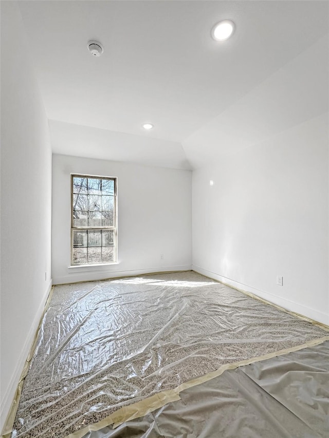 spare room with recessed lighting, lofted ceiling, and baseboards