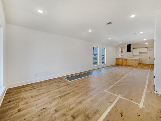 unfurnished living room with visible vents, recessed lighting, light wood-style floors, baseboards, and vaulted ceiling
