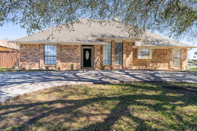 single story home with brick siding, a shingled roof, and a front lawn