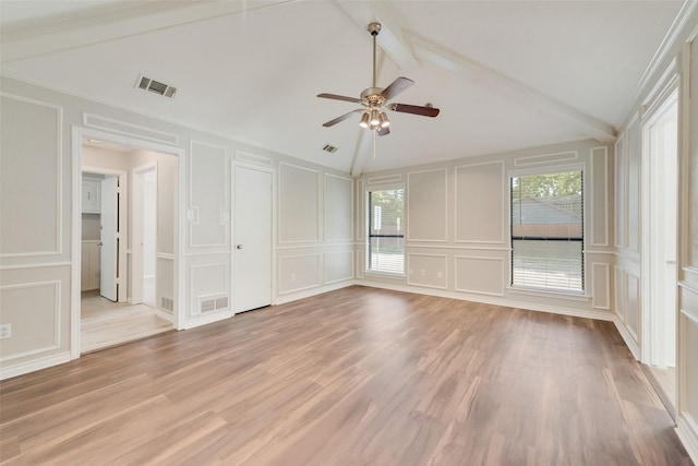 unfurnished bedroom with light wood-style floors, lofted ceiling with beams, a decorative wall, and visible vents