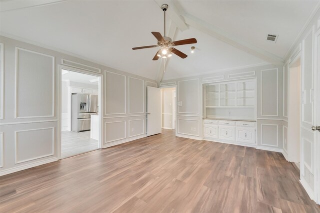 unfurnished bedroom featuring lofted ceiling with beams, a decorative wall, stainless steel refrigerator with ice dispenser, and visible vents