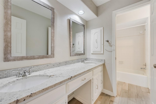 full bath featuring baseboards, double vanity, shower / bath combination, and a sink