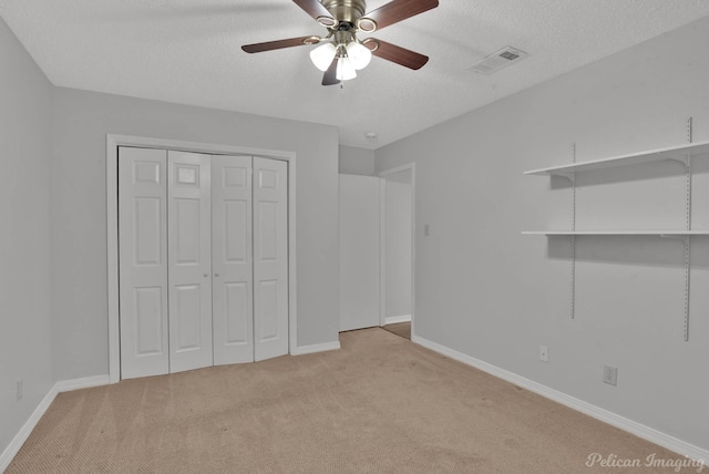 unfurnished bedroom featuring visible vents, a closet, light colored carpet, and a textured ceiling