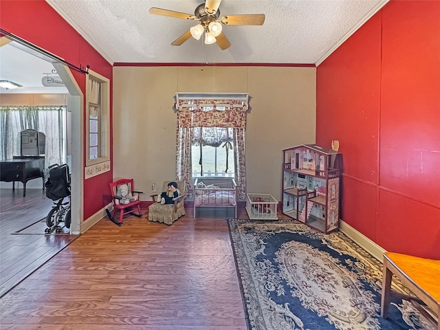 playroom with a textured ceiling, ceiling fan, wood finished floors, and ornamental molding