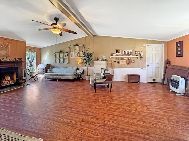living room with heating unit, a lit fireplace, a ceiling fan, vaulted ceiling with beams, and wood finished floors