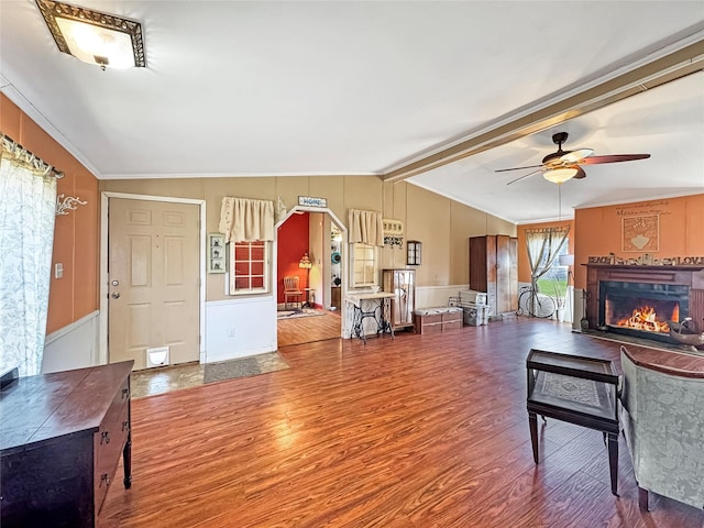 living room with vaulted ceiling with beams, a lit fireplace, ceiling fan, and wood finished floors