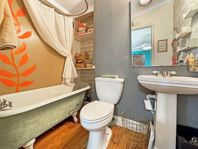 full bathroom with a soaking tub, baseboards, toilet, wood finished floors, and a sink
