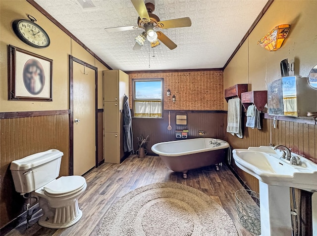 1791 County Road 3855, Poolville, TX 76487 - full bathroom with wood finished floors, wainscoting, toilet, crown molding, and a soaking tub