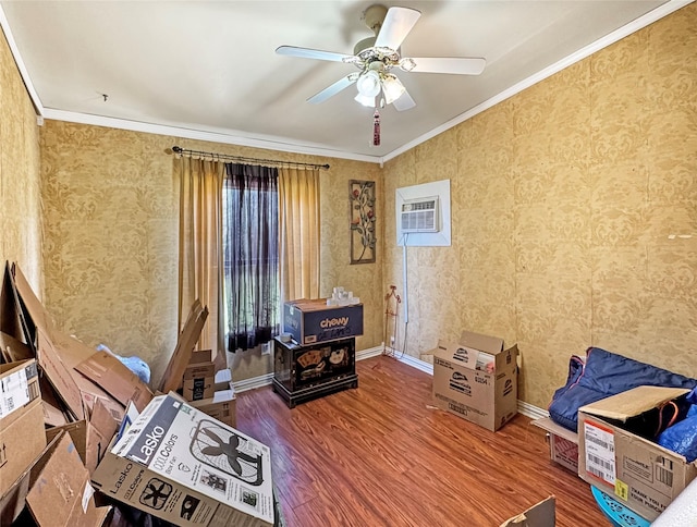 sitting room with a wall unit AC, ornamental molding, baseboards, a ceiling fan, and wood finished floors