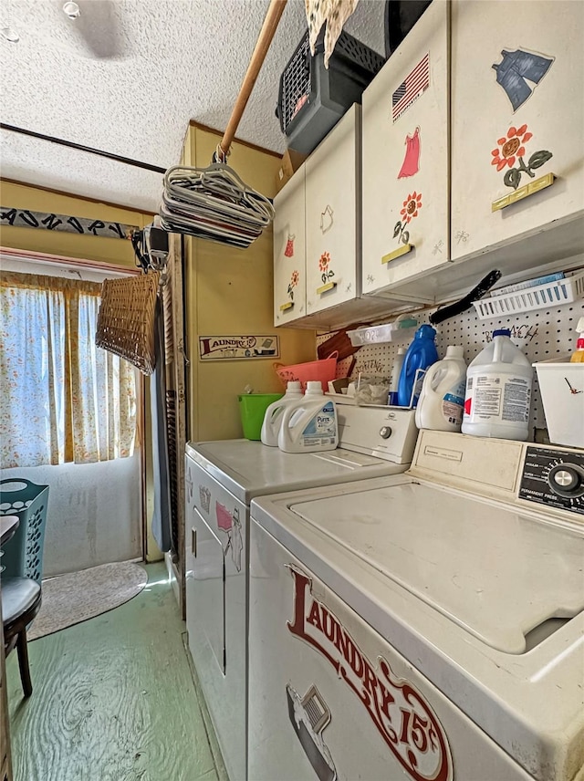 clothes washing area featuring a textured ceiling, cabinet space, and washing machine and dryer
