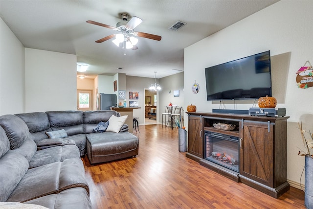 1017 Story Book Ln, Weatherford, TX 76086 - living room featuring wood finished floors, visible vents, and ceiling fan with notable chandelier