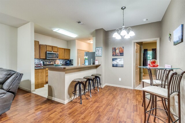 1017 Story Book Ln, Weatherford, TX 76086 - kitchen featuring light wood-type flooring, stainless steel appliances, brown cabinetry, and a breakfast bar area