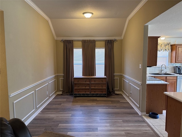 unfurnished dining area with dark wood finished floors, vaulted ceiling, crown molding, and a sink