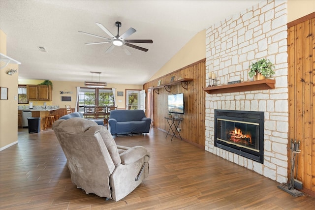 251 Dunn Dr, Palo Pinto, TX 76484 - living room with a stone fireplace, ceiling fan, wood finished floors, wood walls, and vaulted ceiling