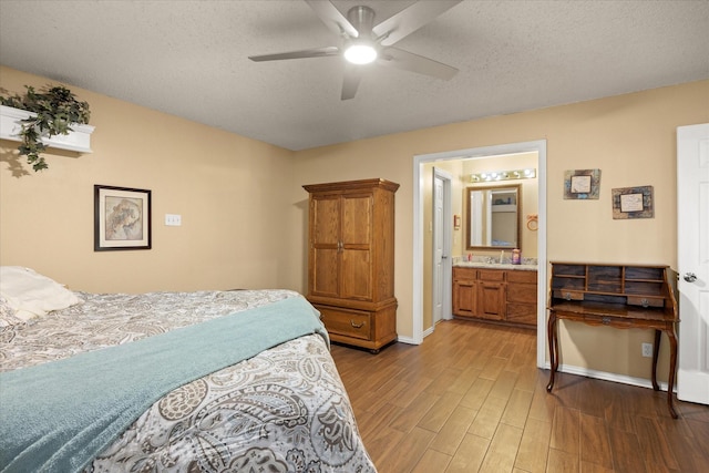 251 Dunn Dr, Palo Pinto, TX 76484 - bedroom featuring light wood-style flooring, baseboards, a textured ceiling, ensuite bath, and a ceiling fan
