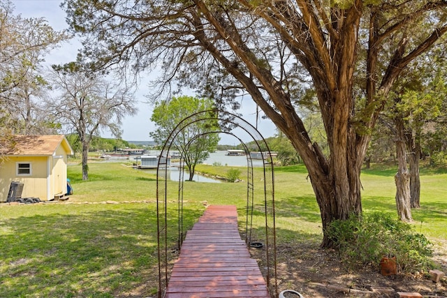 251 Dunn Dr, Palo Pinto, TX 76484 - view of grassy yard with a water view, a storage shed, and an outbuilding