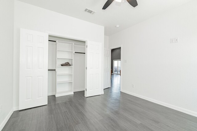 unfurnished bedroom featuring dark wood-style floors, visible vents, a closet, and baseboards