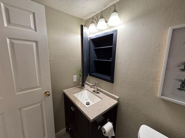 128 W Way Dr, Allen, TX 75002 - bathroom with a textured ceiling, toilet, vanity, and a textured wall