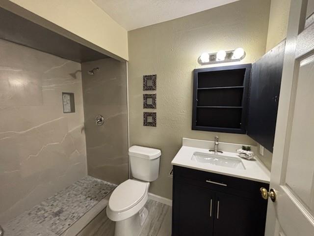 128 W Way Dr, Allen, TX 75002 - full bath with vanity, baseboards, walk in shower, toilet, and a textured wall
