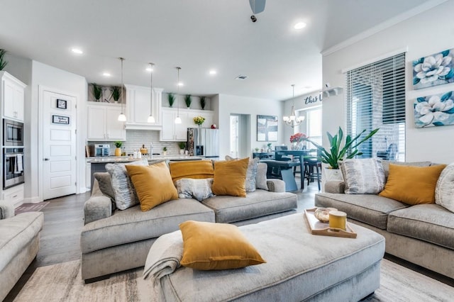 living room featuring recessed lighting, light wood-type flooring, and a notable chandelier