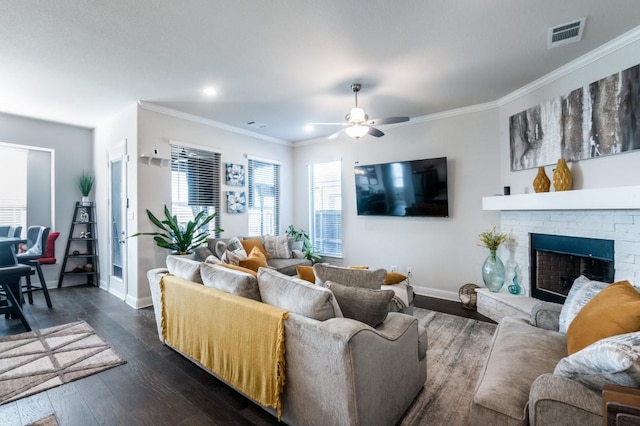 living room featuring ceiling fan, ornamental molding, baseboards, visible vents, and dark wood-style floors
