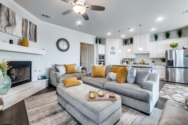 living room featuring visible vents, a ceiling fan, crown molding, and wood finished floors