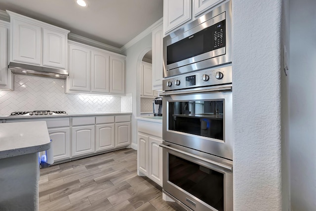 304 Welch Folly Ln, Aledo, TX 76008 - kitchen featuring appliances with stainless steel finishes, under cabinet range hood, crown molding, white cabinetry, and decorative backsplash