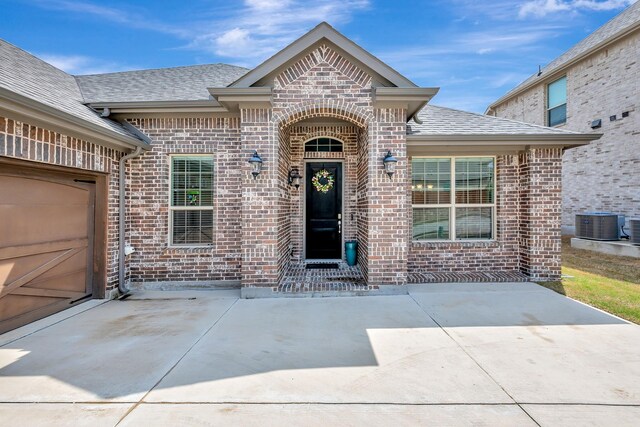 304 Welch Folly Ln, Aledo, TX 76008 - view of exterior entry featuring brick siding, a shingled roof, and central air condition unit