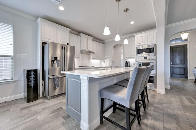 304 Welch Folly Ln, Aledo, TX 76008 - kitchen with appliances with stainless steel finishes, arched walkways, ornamental molding, tasteful backsplash, and a breakfast bar area