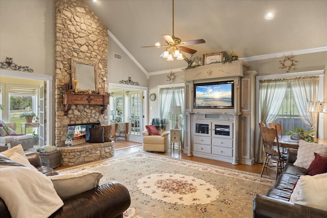 living room featuring high vaulted ceiling, visible vents, a fireplace, ceiling fan, and light wood finished floors