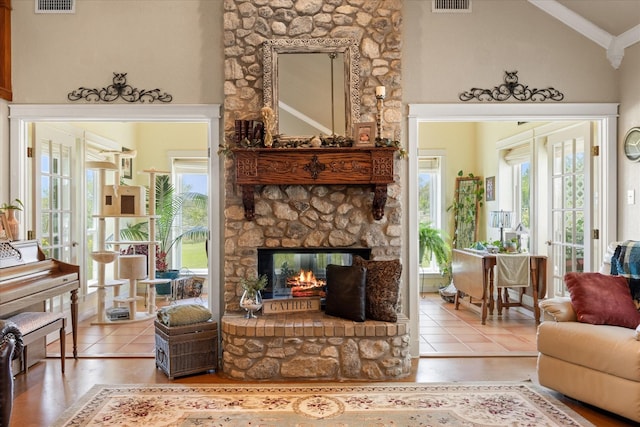 tiled living room featuring lofted ceiling, ornamental molding, a healthy amount of sunlight, and visible vents