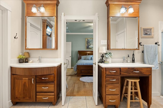 ensuite bathroom featuring a sink, ensuite bath, tile patterned flooring, two vanities, and baseboards