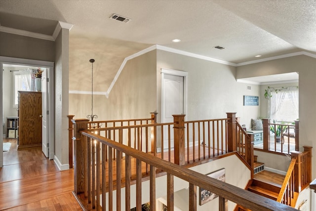 hallway featuring wood finished floors, baseboards, an upstairs landing, and visible vents