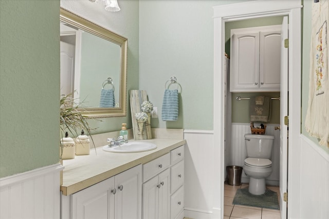 bathroom with vanity, toilet, a wainscoted wall, and tile patterned floors